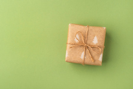 A Christmas gift wrapped in eco-friendly packaging on a green backgroundの写真素材