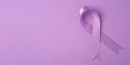 Lilac ribbon on purple background. World Cancer Day on February 4.