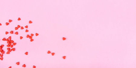 Tiny red hearts on pink background. Valentine's day concept. Top view.の写真素材