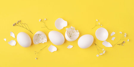 Minimalistic Easter background. White Easter eggs, shells and flowers on a bright yellow background....