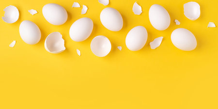 Minimalistic Easter background. White Easter eggs and shells on a bright yellow background. Card...