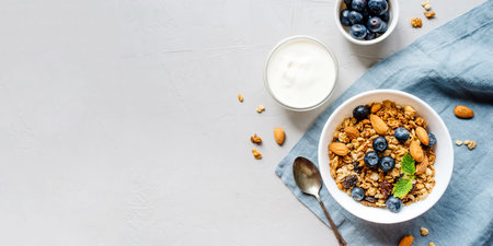 Baked granola with yogurt and blueberries on a gray table. Top view.