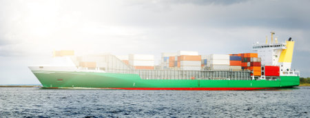 Large cargo container ship leaving the port, sailing in a still sea water. Panoramic view. Freight...