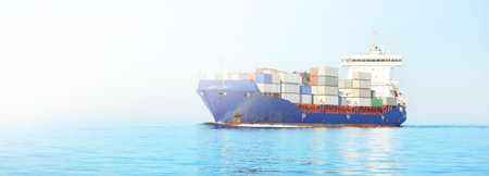 Large cargo container ship sailing in an open sea on a clear day. Panoramic view. Freight...