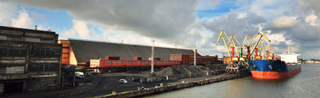 Large blue bulker ship loading coal in the Ventspils free port, Latvia, Baltic sea, Europe. Freight transportation, nautical vessel, fuel generation, global communications, logistics. Panoramic viewの写真素材