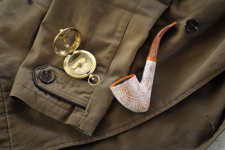 Antiquarian golden compass (sundial), elegant smoking pipe and the old brown overcoat close-up. Vintage still life. Sailing, travel accessories, concept art, collecting, graphic resourcesの写真素材
