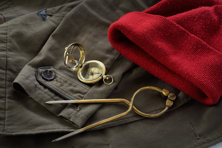 Golden sundial, antique W & HC 6 "brass dividers calipers nautical navigation chart toolÐ± red knitted hat, old brown overcoat close-up. Vintage still life. Sailing, travel accessories, concept artの写真素材
