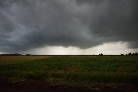 Country agricultural field after the rain. Dramatic sky, epic cloudscape. Fickle weather. Latvia. Cyclone, storm, meteorology, ecology, climate change, natural phenomenonの写真素材