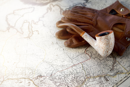 Elegant smoking pipe, tobacco, brown leather gloves, old white nautical chart close-up. Vintage still life. Travel gentleman set. Planning travel, sailing, adventure, concept artの写真素材