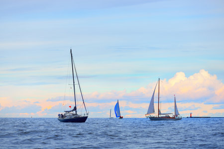 Blue sloop rigged sailboat, vintage wooden two mast yacht (yawl) and other yachts anchored off the...