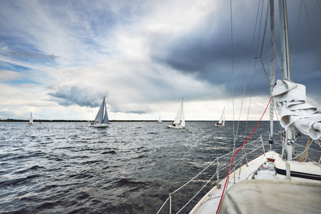 Sailing yacht regatta. Modern sailboat racing through the waves. Dramatic sky with flowing sun rays before the thunderstorm. Terrific cloudscape. North Germany, Kielの写真素材