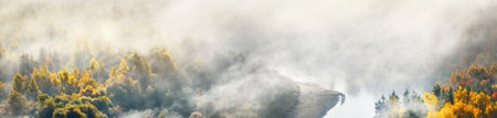 Gauja river valley and golden forest in a clouds of thick mysterious morning fog at sunrise. Sigulda, Latvia. Breathtaking panoramic aerial view. Pure nature, environmental conservation, ecotourismの写真素材