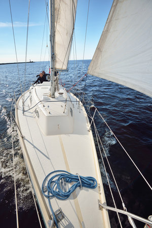 A couple of people on the white yacht sailing on a clear day. Top down view from the bow to the deck, mast and sails. Recreation and summer sport theme. Ruhnu island, Estoniaの写真素材