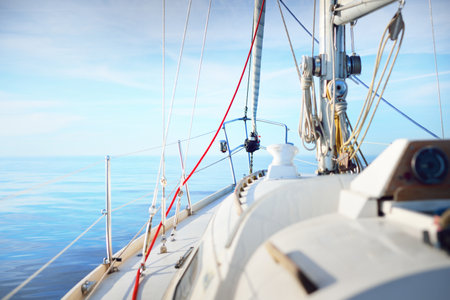 White yacht sailing in a still water on a clear summer day. Close-up view from the deck to the bow, mast and sails. Reflections on the water. Idyllic seascape. Ruhnu island, Estonia, Baltic seaの写真素材