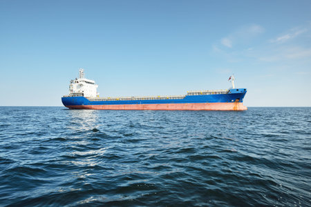 Large blue cargo ship anchored in Strait of Gibraltar. A view from the yacht, close-up. Summer Atlantic sailing near Spain and Africa. Freight transport, logistics, global communications themeの写真素材