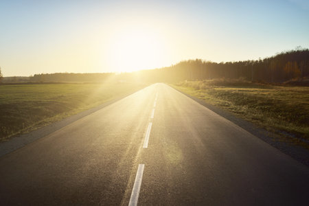An open highway on a hot summer day at sunset. Forest in the background. Driving a car through the...