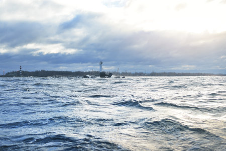 A lighthouse under the dark clouds after the thunderstorm. A view from the sailing boat. Dramatic...