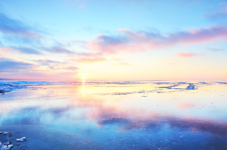 Panoramic view of the snow-covered shore of the frozen Saima lake at sunset. Ice fragments close-up. Colorful cloudscape. Symmetry reflections on the water. Finlandの写真素材