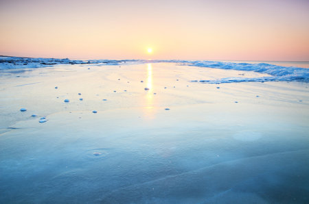 Panoramic view of the snow-covered shore of the frozen Saima lake at sunset. Stunning pink...