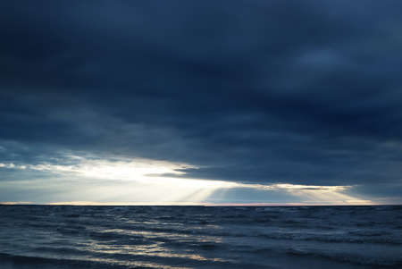 Stormy Baltic sea under dramatic sunset clouds. A view from the sandy shore. Riga bay, Latvia. Epic seascape. Dark autumn scene. Meteorology, ecology, environmental conservation, climate changeの写真素材
