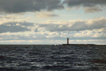 A lonely lighthouse under the dramatic sunset sky after the rain. Baltic sea, Riga bay, Latvia. Epic cloudscape. Transportation, sailing, navigation conceptsの写真素材