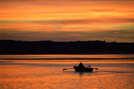Epic red sunset sky above the lake and forest in autumn. Dramatic cloudscape. Symmetry reflections...