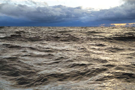 A view to the North sea from a sailing boat at sunset. Dramatic stormy sky, sun rays through the dark clouds. Epic seascape. Deep cyclone in winter. Norway. Concept image, climate change, ecologyの写真素材