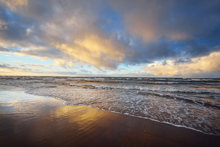 Colorful sunset clouds above the Baltic sea, cyclone in winter. Dramatic sky, waves and water splashes. Germany. Ecology, climate change, global warming conceptsの写真素材