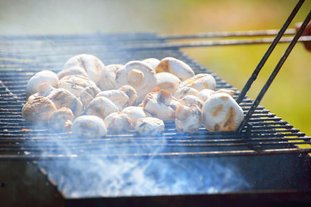 Charcoal grilled champignon mushrooms and smoke close-up. Culinary, healthy eating, lifestyle, organic, vegetarian, vegan food, cooking, summer vacations themeの写真素材