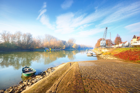 An empty alley through the park near Rhine river. No people because of travel ban and coronavirus (COVID-19) outbreak. Old port crane in the background. Quarantine zone in Mainz, Germanyの写真素材