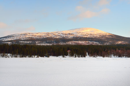 Ice pressure ridge on a frozen lake shore. Mountain peaks in the background. Dramatic cloudscape. Picturesque winter scenery. Ecology, environment, climate change. Kola Peninsula, Karelia, Russiaの写真素材