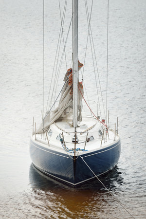 Blue sloop rigged yacht anchored in shallow water near the sandy shore. Top down view. Leisure activity, sport, recreation theme. Glomma river, Oslofjord, Norwayの写真素材