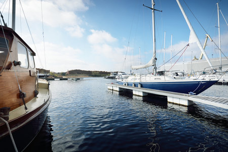 Elegant and modern sailing boats (for rent) moored to a pier in a yacht marina on a clear day....