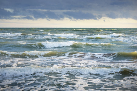 Baltic sea after a thunderstorm at sunset. Ventspils, Latvia. Colorful glowing clouds. Waves and...