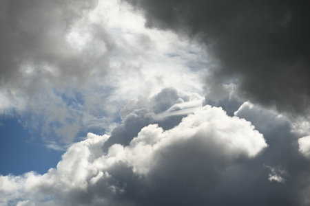Clear blue sky with glowing white cumulus clouds after thunderstorm at sunset. Dramatic cloudscape....