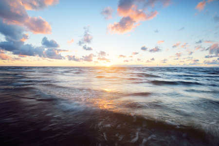 Epic colorful glowing pink sunset clouds above the sea after a thunderstorm. Dramatic sky. Waves and water splashes texture. Idyllic seascape. Concept image, long exposure. Picturesque sceneryの写真素材