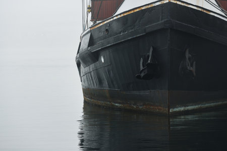 Historic cargo boat moored to a pier, close-up. Heavy morning fog. Kiel, Germanyの写真素材