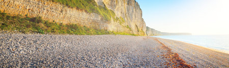 White cliff on the rocky shore of English Channel at sunset. FÃ©camp, Normandy, France. Clear blue...