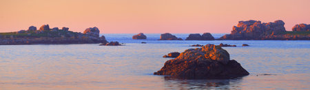 Panoramic view of the rocky shore of Lilia bay at sunset. Plouguerneau, FinistÃ¨re, Brittany, France. Clear pink sky. Travel destinations, landmarks, recreation, nature. Idyllic landscapeの写真素材