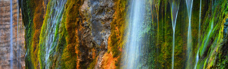 Waterfall close-up, an orange cliff with green moss. Etretat, Normandy, France. Colorful abstract nature pattern, texture, panoramic background, wallpaper, graphic resource. Environment, pure natureの写真素材