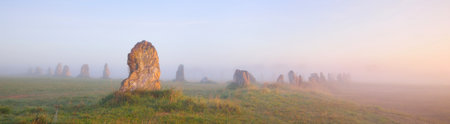 Menhir alignment view at Camaret sur mer in a morning fog at sunrise. Brittany, France. Golden light. Panoramic picturesque scenery. Travel destinations, national landmarks. sightseeing, historyの写真素材