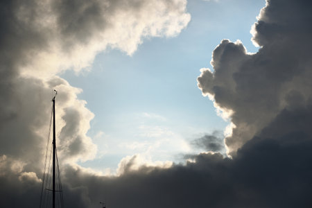 Terrific cloudscape. Sailing in a thunderstorm, mast close-up. Dramatic sky. Sunlight through the...