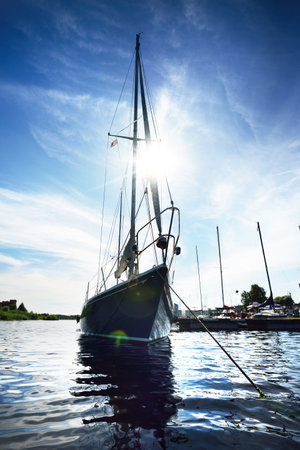 Blue sloop rigged yacht moored to a pier on a clear summer day, close-up. A view from the water....