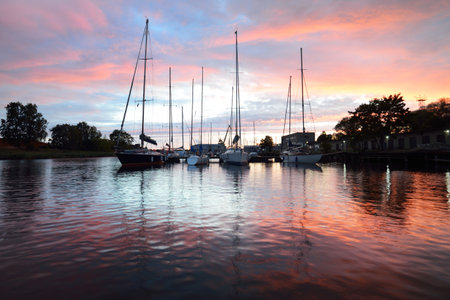 Yachts and boats moored to a pier at sunset, close-up. Dramatic evening sky with colorful clouds....