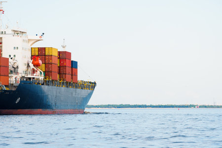 Large cargo container ship leaving the port of Norfolk, close-up. Cloudy blue sky. Virginia, USA