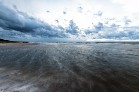 Dark cloudy sky above the Baltic Sea, Denmark. Storm waves and colorful clouds. Long exposureの写真素材