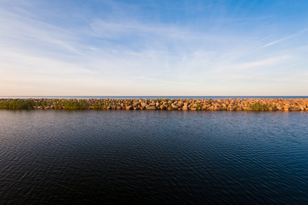 Rocky seashore at sunset. Clear blue evening sky with white clouds and plane tracks. Baltic sea, Ruhnu island, Estoniaの写真素材