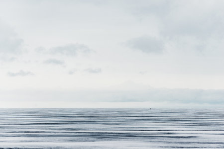 Winter landscape. A view of the frozen snow-covered lake. Forest in the background. Stormy evening clouds. Onega lake, Karelia, Russiaの写真素材