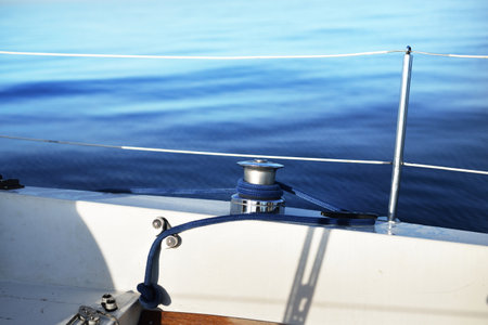 White yacht sailing at sunset. A blue winch close-up. Waves and clouds. Baltic sea