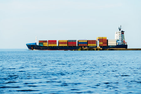 Large cargo container ship close-up. Lighthouse in the background. Baltic sea, Latviaの写真素材